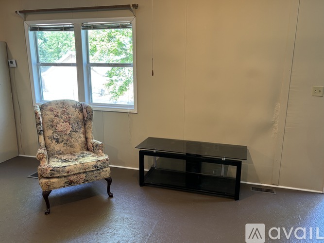 A living room with a floral sofa and matching armchair, a coffee table, and a large bookshelf.