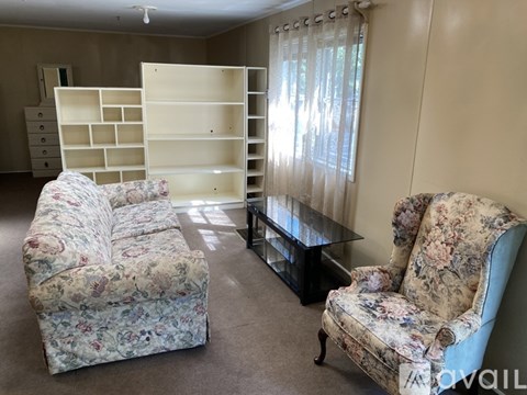 A living room with a floral sofa and matching armchair, a coffee table, and a large bookshelf.