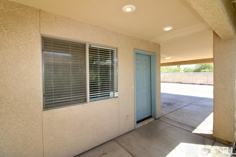 A blue door is on the right side of a tan building.