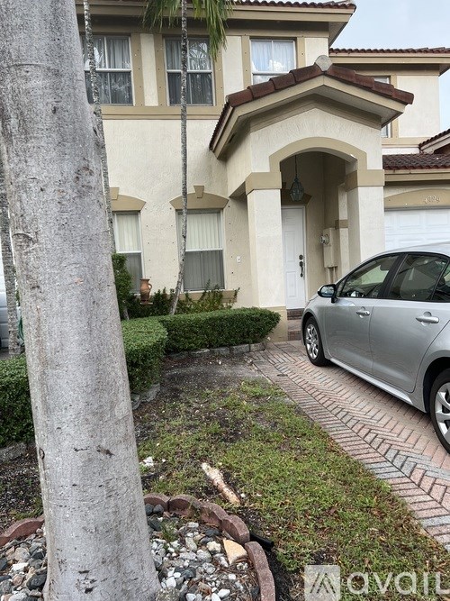 A silver car is parked in front of a house.