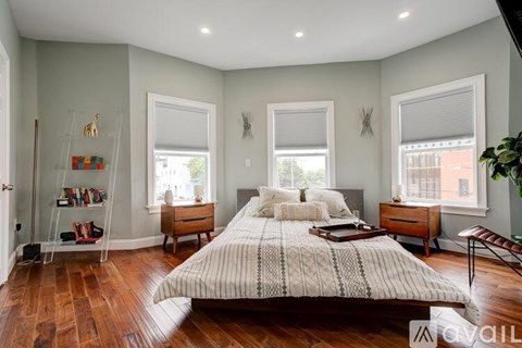 A bedroom with a large bed, a chair, and a window.
