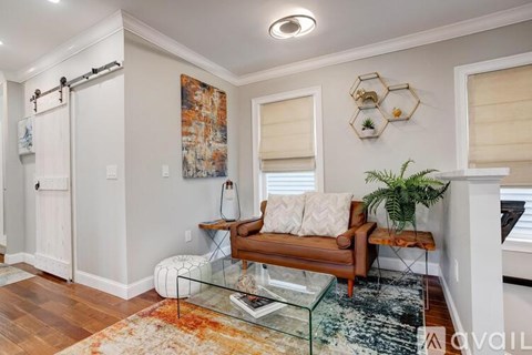 A living room with a couch, a rug, and a painting on the wall.