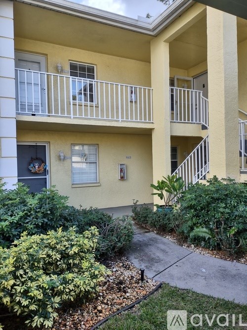 A yellow building with a balcony and a small garden in front.