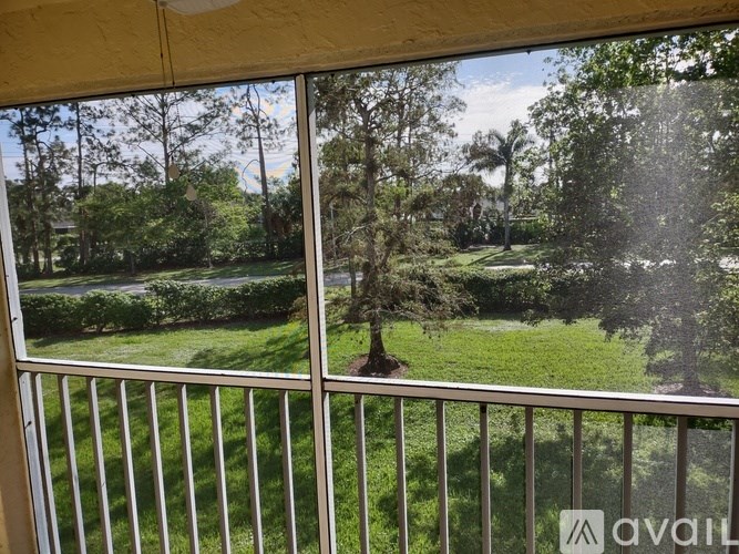 A view from a balcony looking out at a lush green lawn and trees.