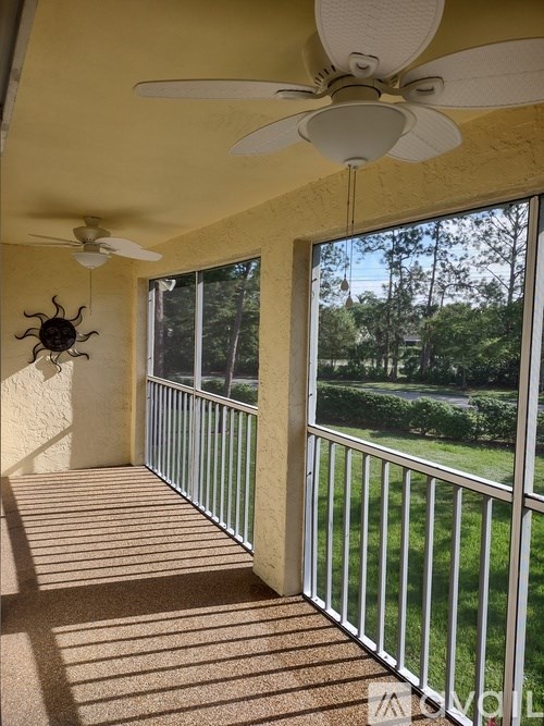 A sunroom with a ceiling fan and a metal railing.