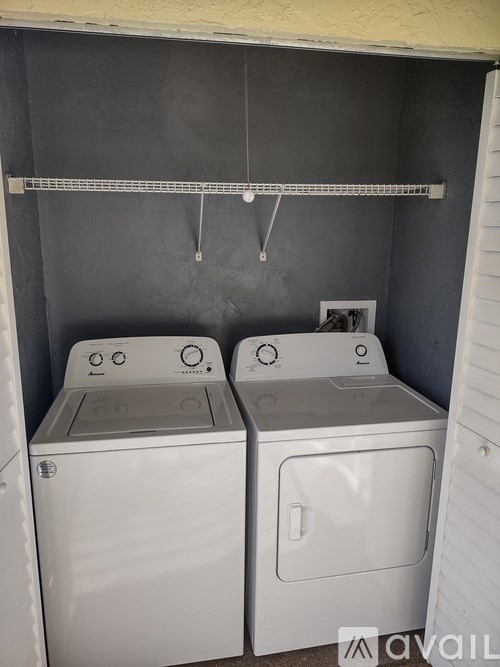 Two white washing machines in a small laundry room.