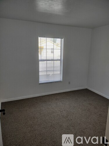 A room with a carpeted floor and a window with blinds.