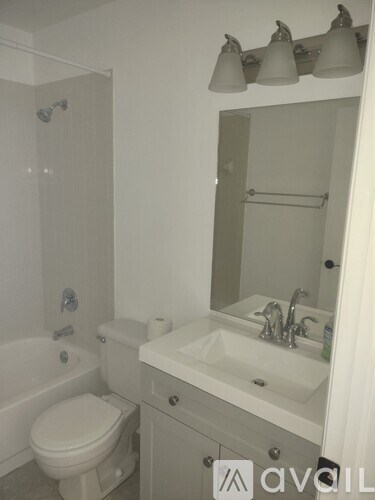 A white bathroom with a toilet, sink, and mirror.