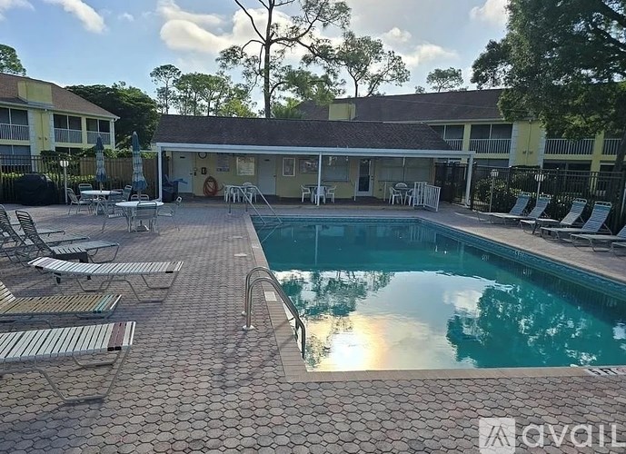 A pool area with sun loungers and a building in the background.