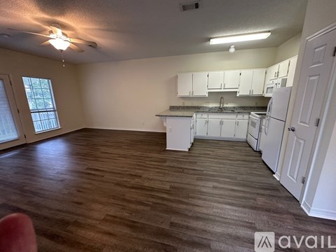 A kitchen with white cabinets and a wooden floor.