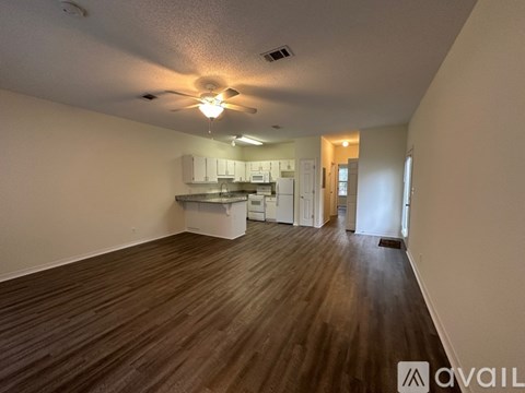 A spacious room with wooden flooring and a ceiling fan.