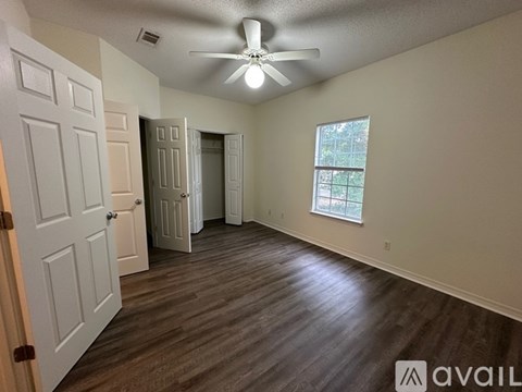 A room with a ceiling fan and wooden flooring.