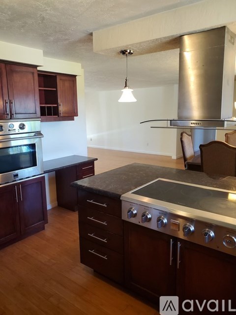 A kitchen with dark wood cabinets and a stainless steel range hood.