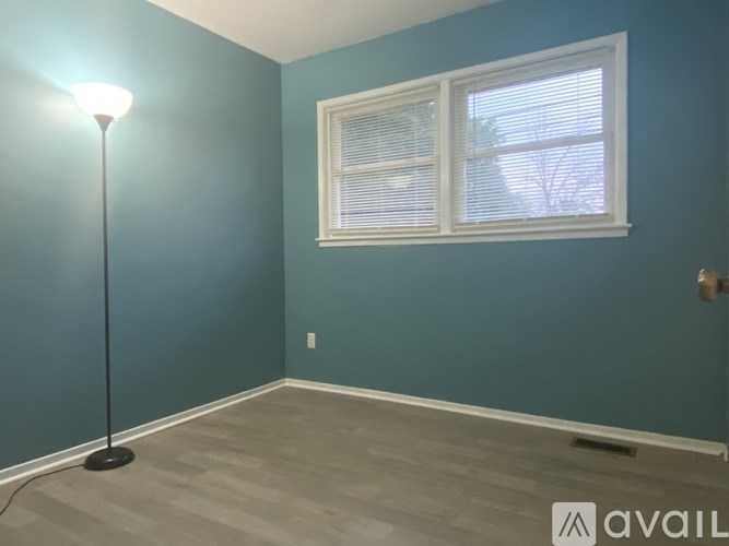 A room with a blue wall and a window with blinds.