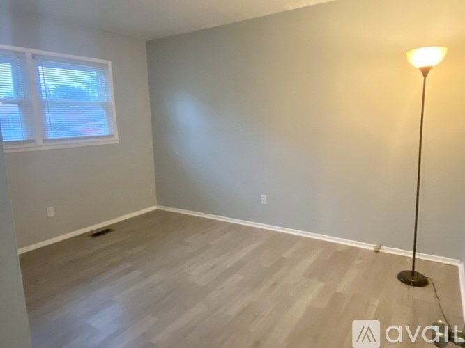 A room with a wooden floor and a floor lamp.