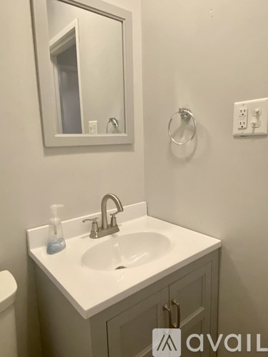 A white sink with a soap dispenser and a mirror above it.