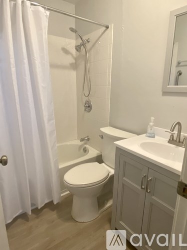 A white toilet is in a bathroom with a white shower curtain.