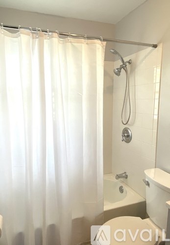 A white bathroom with a shower curtain and a bathtub.