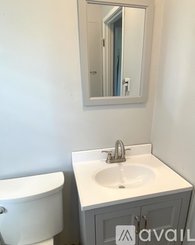 A white sink is in a cabinet under a mirror.