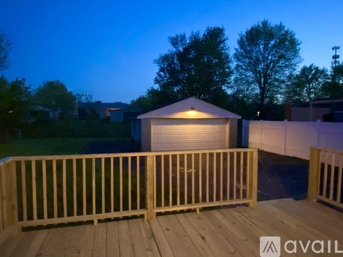 A wooden deck with a lit-up garage in the background.