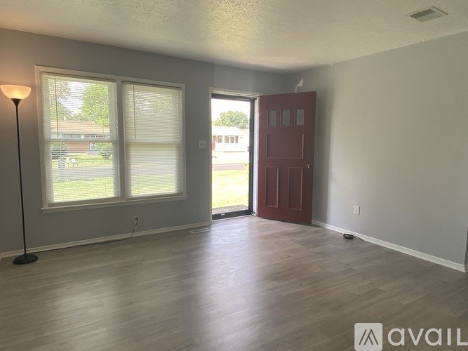 A room with a red door and a floor lamp.