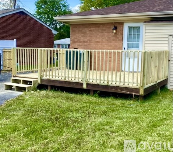 A wooden deck in front of a brick house.