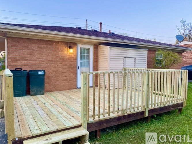 A wooden deck leads to a house with a white door and a window.