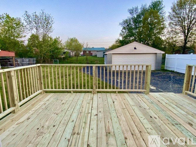A wooden deck with a white fence and a shed in the background.