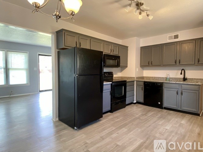 A kitchen with black appliances and wooden floors.