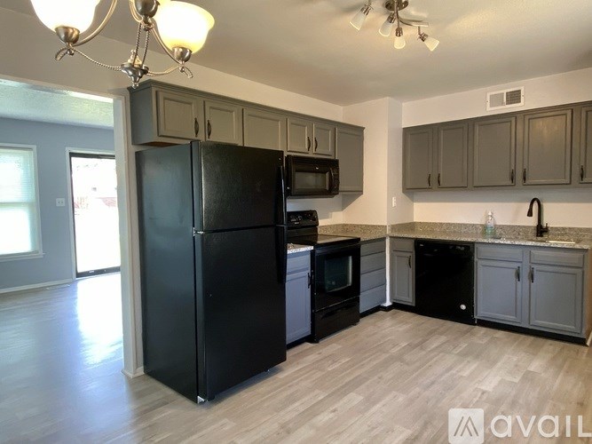 A kitchen with black appliances and wooden floors.