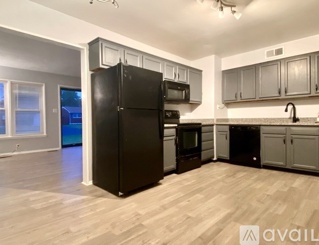 A kitchen with black appliances and wooden floors.