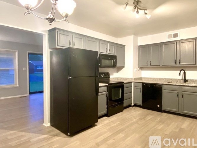 A kitchen with a black fridge, microwave, and oven.
