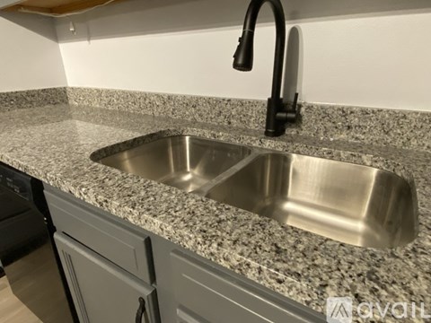 A kitchen sink with a granite countertop and a black faucet.