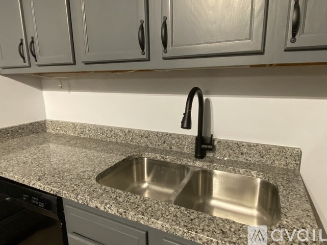 A kitchen with a granite countertop and a stainless steel sink.