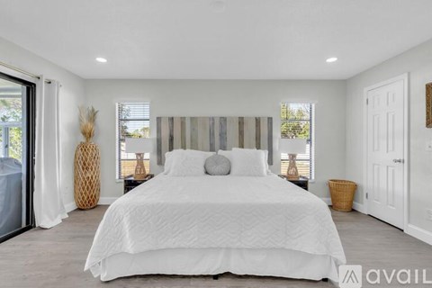 A bedroom with a large bed and a window with blinds.