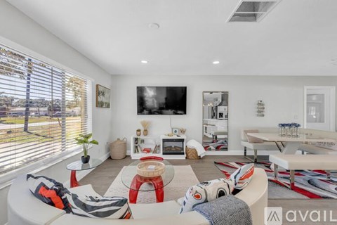 A living room with a white couch and a flat screen TV mounted on the wall.