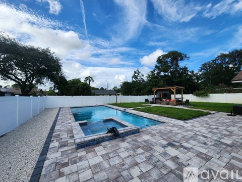 A backyard with a pool and patio area.