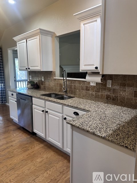 A kitchen with granite countertops and white cabinets.