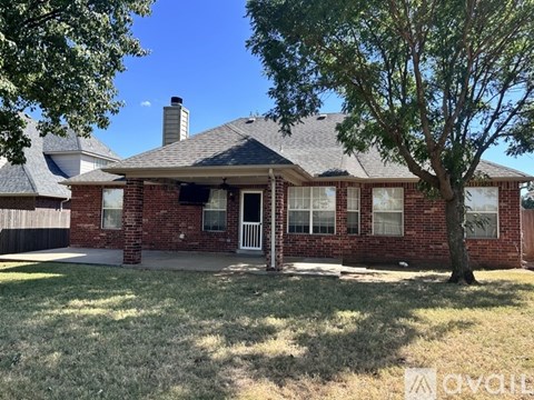 A house with a brick facade and a tree in front.