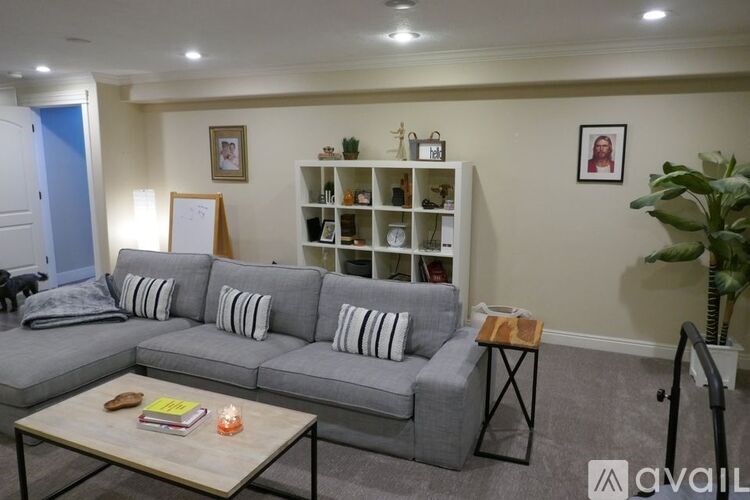 A living room with a grey couch, a coffee table, and a bookshelf.