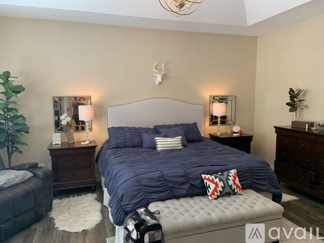 A bedroom with a large bed and a deer head on the wall.