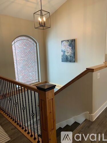 A staircase with a wooden handrail and a window with a patterned glass.