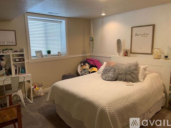 A bedroom with a bed, a desk, and a window with blinds.