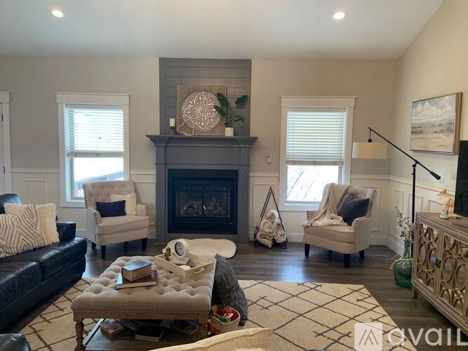 A living room with a fireplace and two chairs.