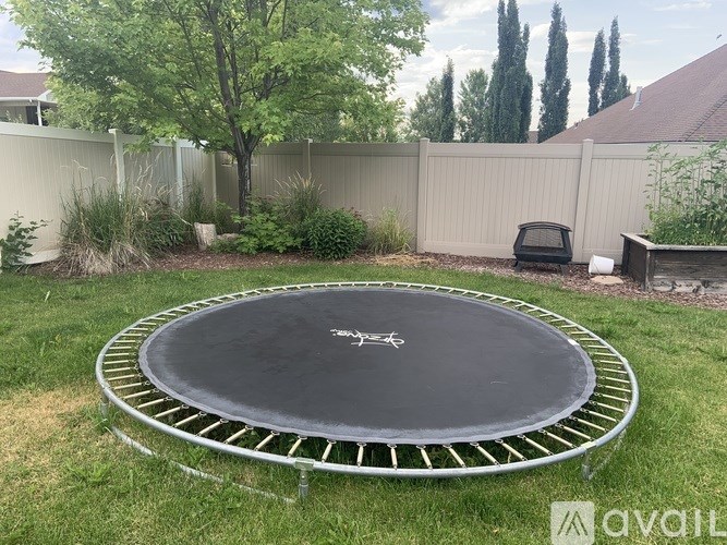 A trampoline in a backyard surrounded by a fence.