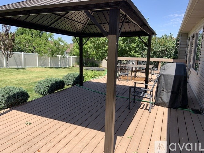 A wooden deck with a black awning and a grill.