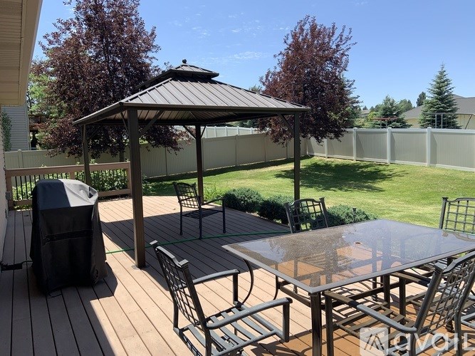 A wooden deck with a gazebo and chairs.