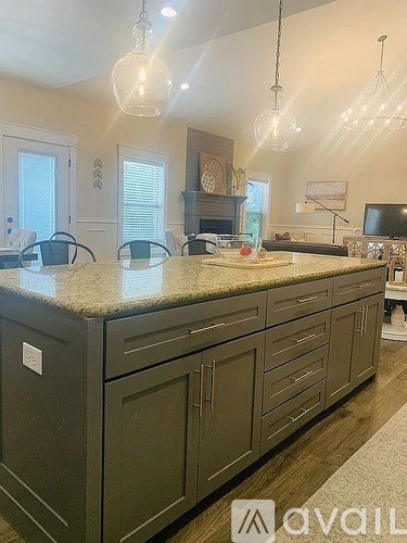 A kitchen with granite countertops and dark cabinets.