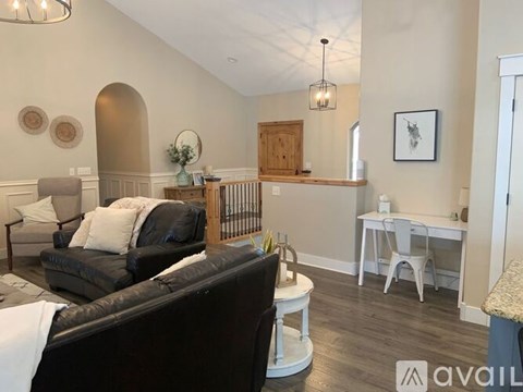 A living room with a black couch and a white chair.