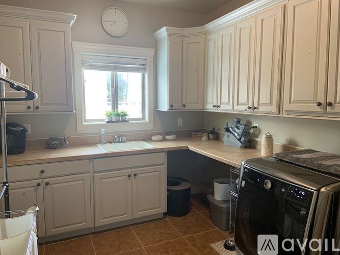 A kitchen with a washing machine and a clock on the wall.